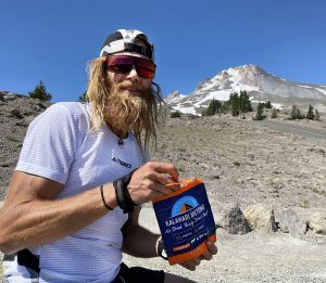 Timothy Olson eating original biltong with snow topped mountain in the background