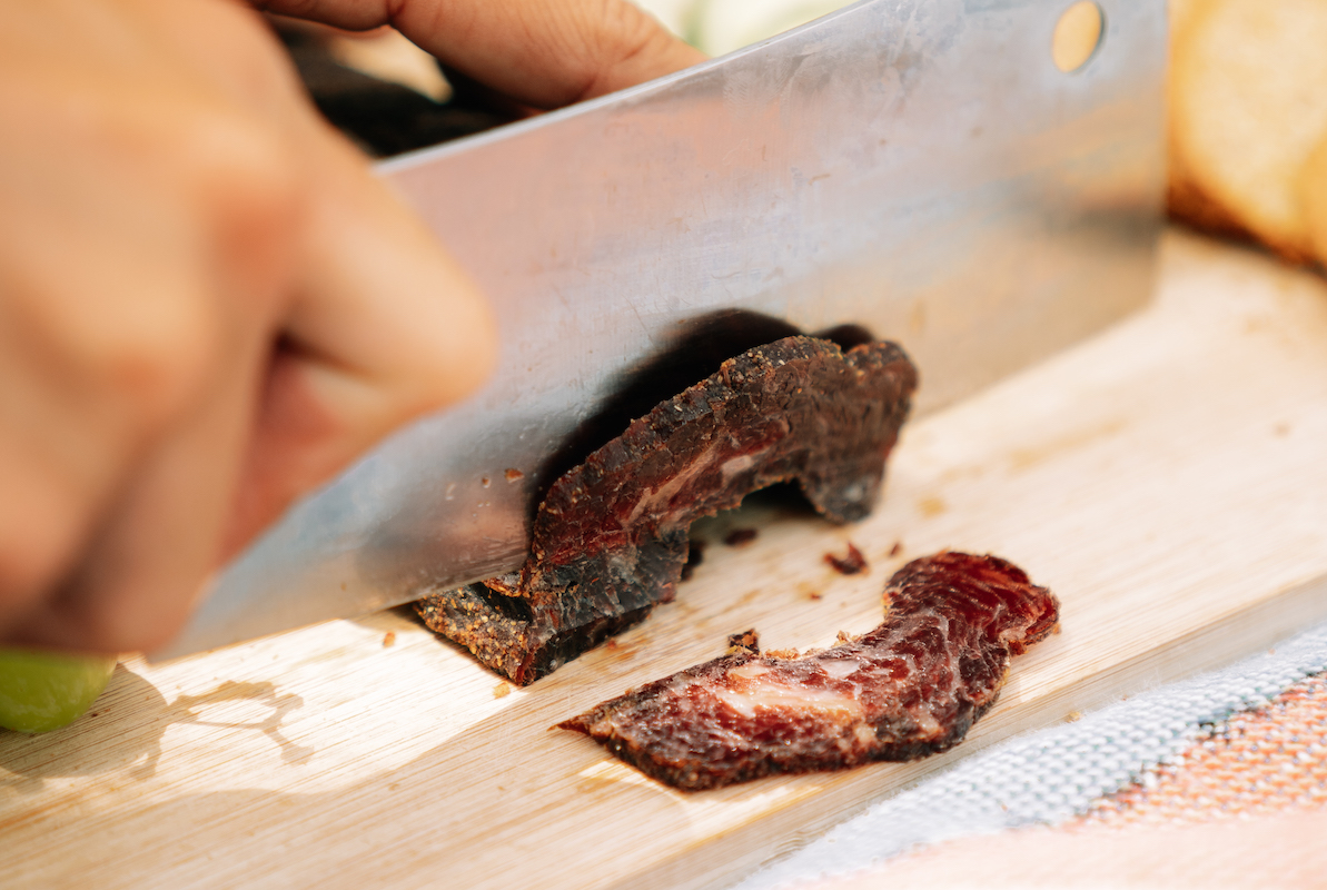 Biltong slab being sliced with a large knife