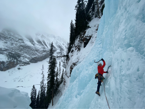 woman in red jacket ice climbing